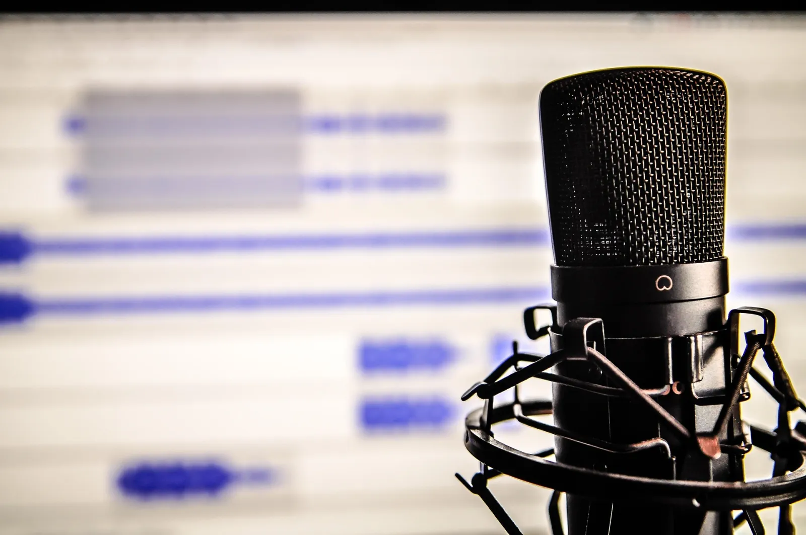 A microphone in front of a blurred audio editor screen